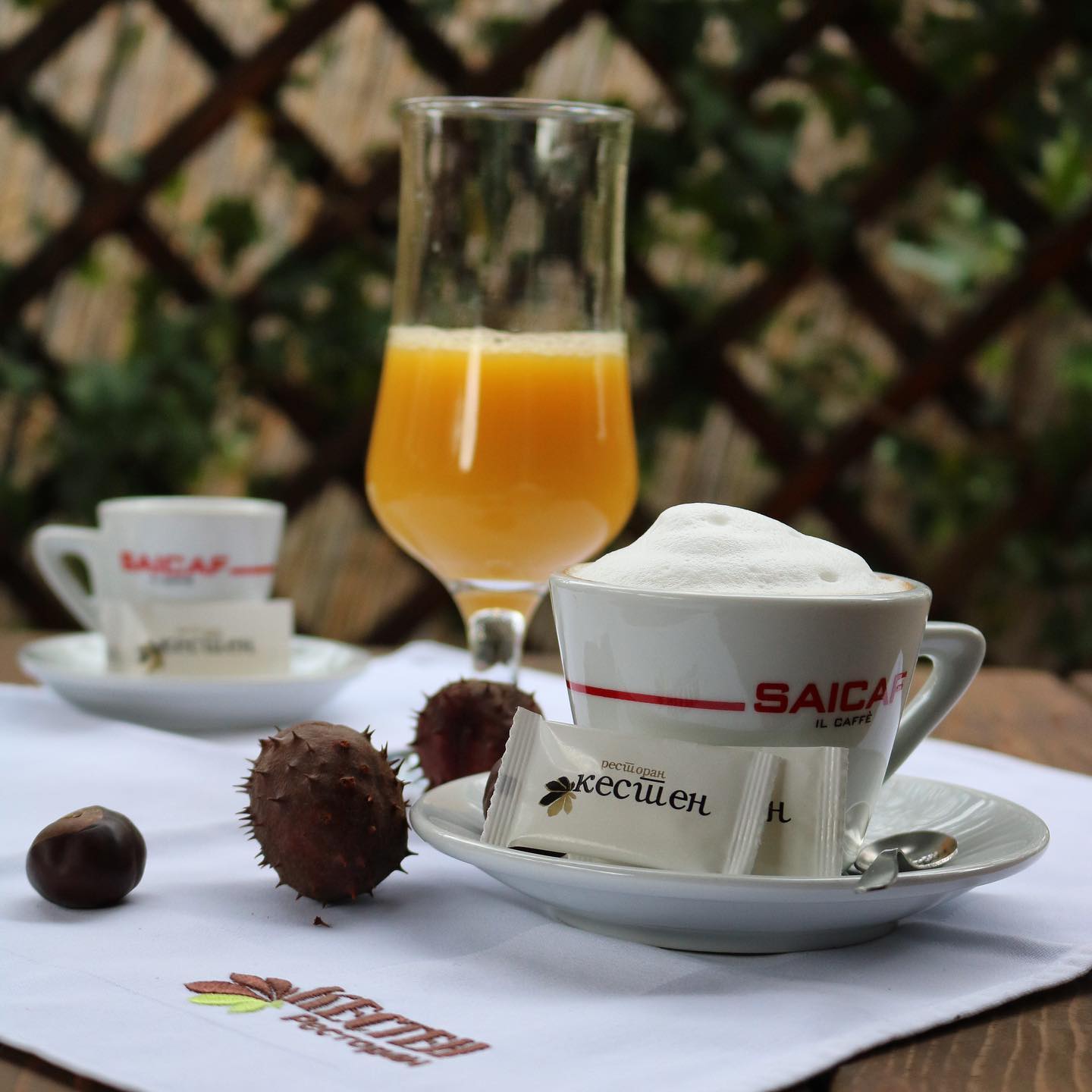 Kafa, ceđeni sok i kesteni na stolu u bašti restorana Kesten, pred zelenom ogradom