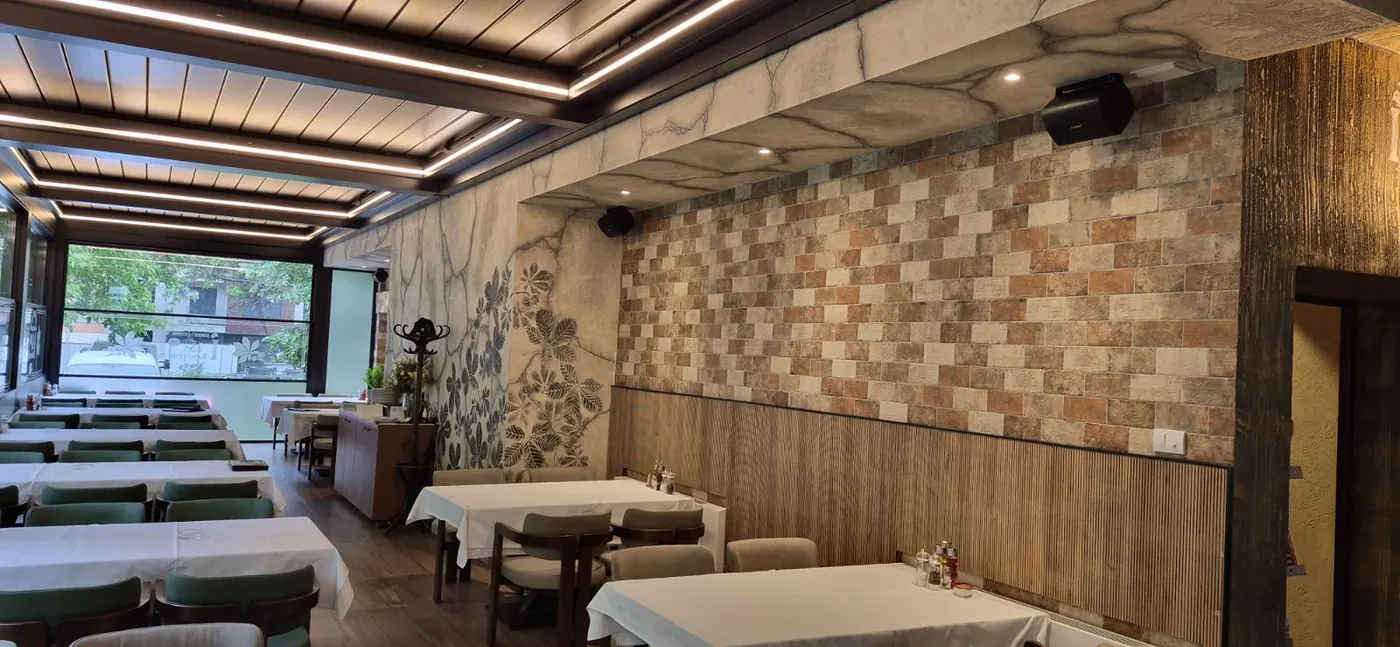 Sala restorana Kesten — drvena tavanica, postavljeni stolovi i staklo koje gleda u zelenilo
